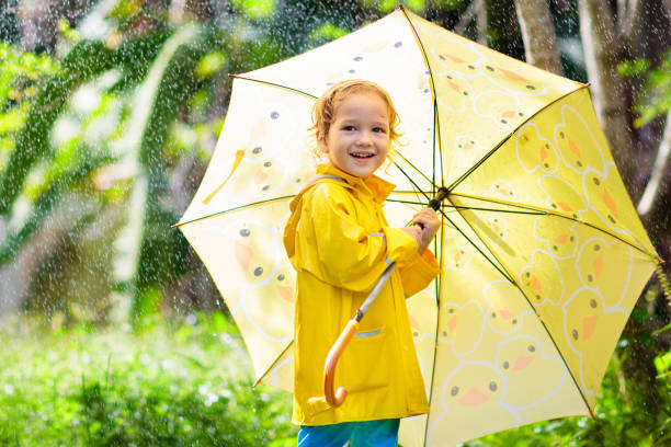 istock Child playing in the rain. Kid with umbrella. 1165762453