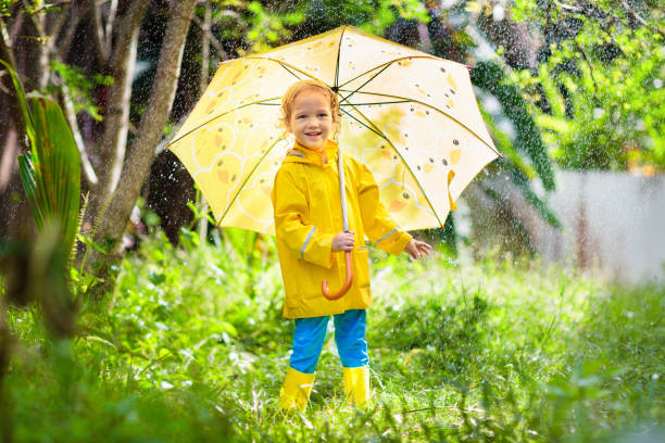 istock Child playing in the rain. Kid with umbrella. 1165763595