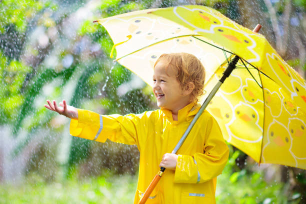 istock Child playing in the rain. Kid with umbrella. 1165763709