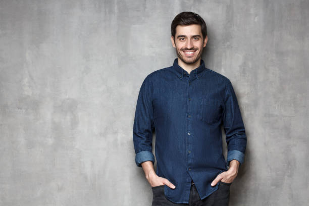 istock Young business man satisfied with his life standing against gray wall with copy space on left side 1165763873