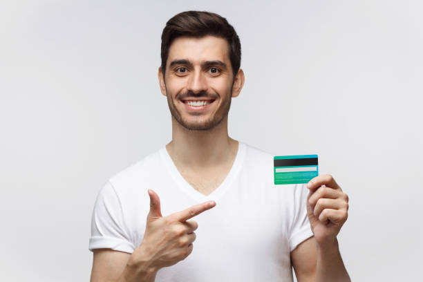 istock Handsome man in white t-shirt showing credit card 1165763901