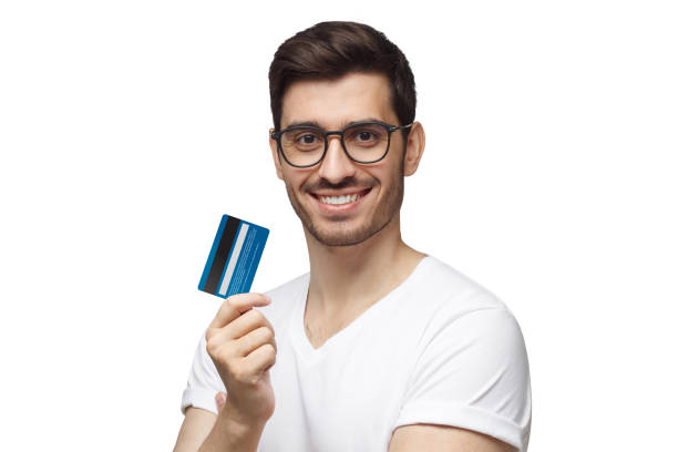 jeune homme heureux de sourire utilisant des lunettes, retenant la carte bleue de crédit, d'isolement sur le fond blanc - internet e commerce credit card retail photos et images de collection