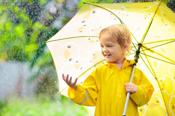 istock Child playing in the rain. Kid with umbrella. 1165764044
