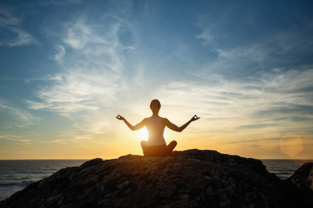 istock Silhouette young woman practicing yoga on the sunset beach. Tranquility and concentration. 1165766692