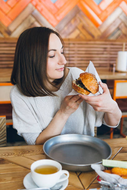 istock Woman eating a freshly prepared delicious Burger 1165769174