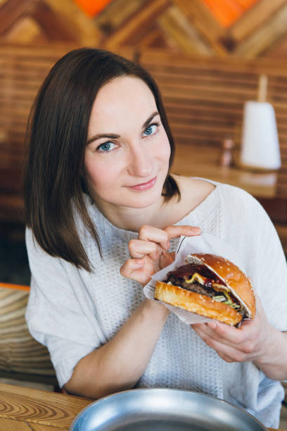 istock Woman eating a freshly prepared delicious Burger 1165769252