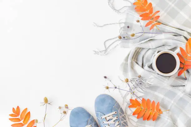 Photo of Flat lay composition with a sneakers, scarf, cup of coffee and colorful autumn leaves on a white background