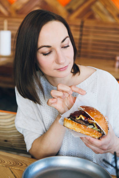 istock Woman eating a freshly prepared delicious Burger 1165769456