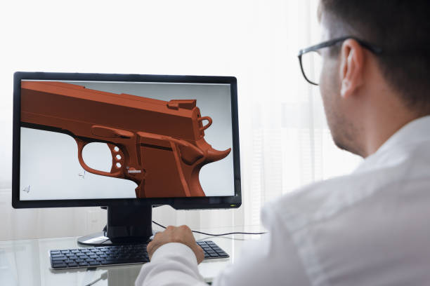 istock LOS ANGELES, CALIFORNIA - JUNE 3, 2019: Engineer, Constructor, Designer, Architect in Glasses Working on a Personal Computer. He Creating New Component of Pistol in CAD Program. Freelance Work. An illustrative editorial image 1165770313