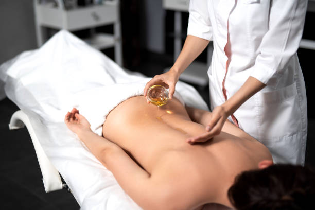 istock Masseuse pouring massage oil on lady back 1165770528