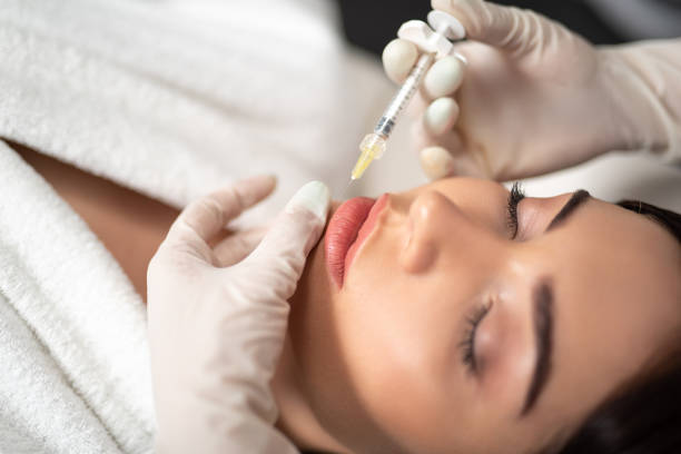 istock Beautician in white sterile gloves making injection in lady lips 1165770545