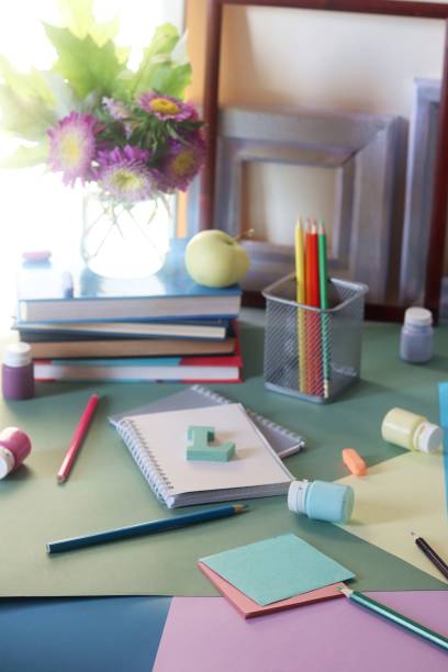 istock Books, flowers, apple, stationery, frames and colored paper on the table 1165772589