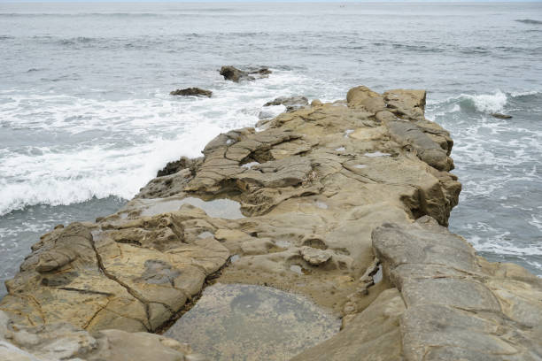 istock Rough water spills onto a rock ledge by a beach cove. 1165774426