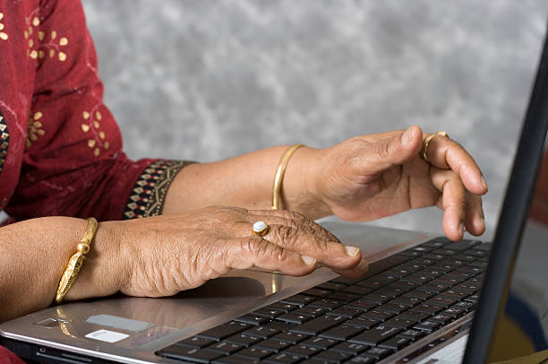 le mani di donna anziana lavorando su computer portatile - indian ethnicity indian culture jewelry gold foto e immagini stock