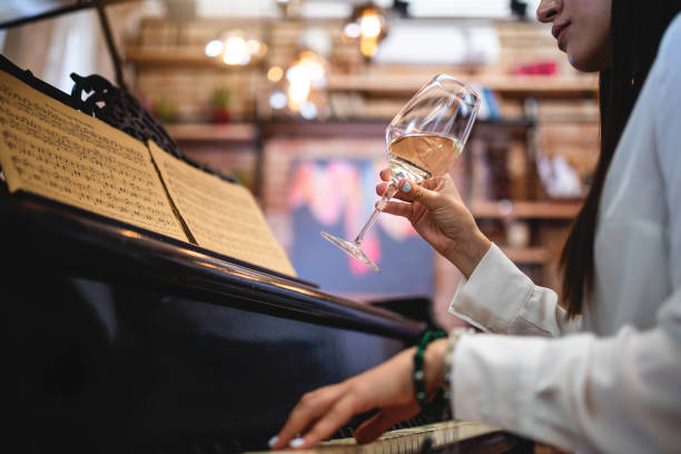 istock Successful female pianist playing the piano and drinking white wine 1165781582