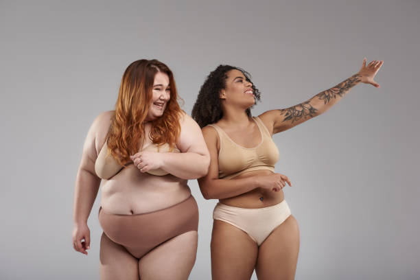 istock Happy plus size female friends looking away in studio 1165783019