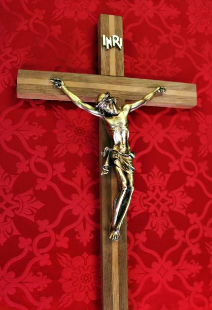 istock Cross with gold figure of Christ on red patterned cloth 1165784110