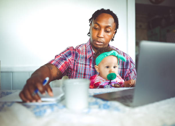 istock African American dad works on a computer with his infant daughter work from home modern masculinity 1165787879