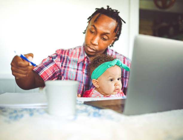 istock African American dad works on a computer with his infant daughter work from home modern masculinity 1165787893