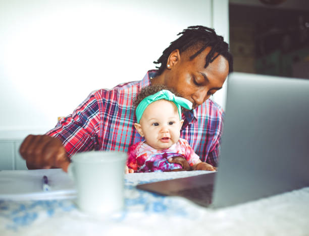 istock African American dad works on a computer with his infant daughter work from home modern masculinity 1165787894