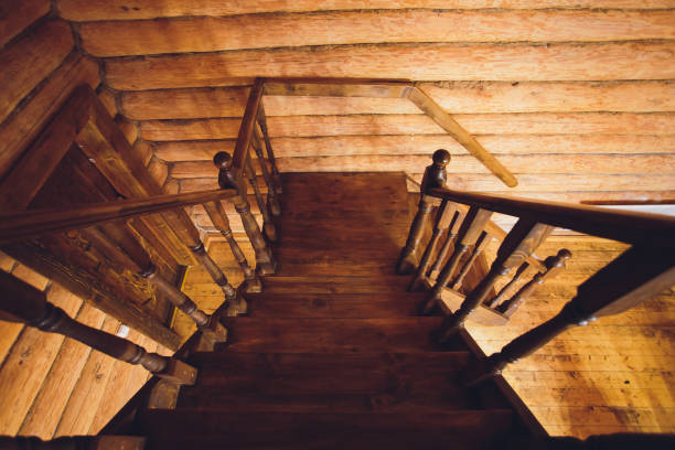 istock Old squared spiral stairway with dark brown wooden handrails, partly lighted by windows. View from the top. 1165788765