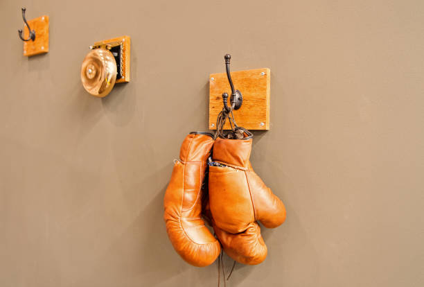 istock For all your boxing needs. Pair of retro sparring boxing gloves hooked on wall. Old protective sportwear for boxing matches and training. Boxing is a combat sport 1165790968