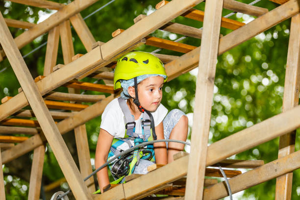 menina feliz da escola que aprecia a atividade em um parque de escalada da aventura em um dia de verão - education high up sport sports helmet - fotografias e filmes do acervo