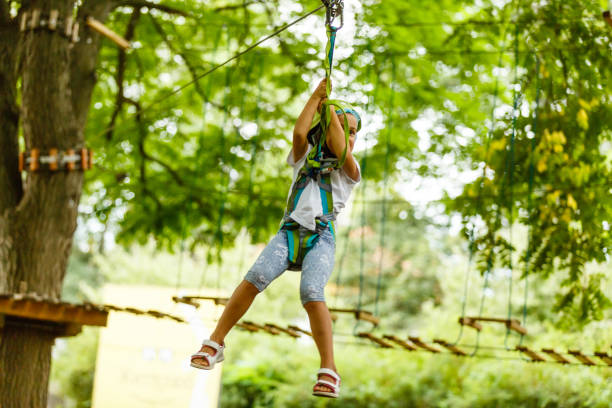 menina feliz da escola que aprecia a atividade em um parque de escalada da aventura em um dia de verão - education high up sport sports helmet - fotografias e filmes do acervo