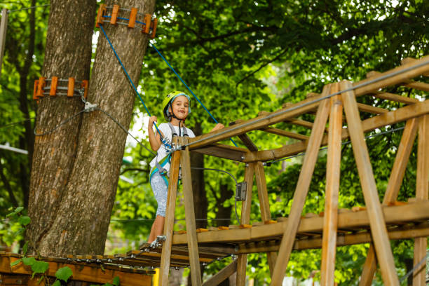 menina feliz da escola que aprecia a atividade em um parque de escalada da aventura em um dia de verão - education high up sport sports helmet - fotografias e filmes do acervo