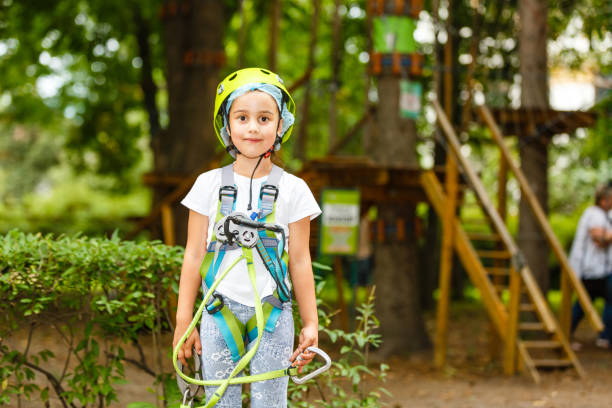 menina feliz da escola que aprecia a atividade em um parque de escalada da aventura em um dia de verão - education high up sport sports helmet - fotografias e filmes do acervo