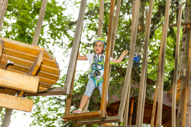 menina feliz da escola que aprecia a atividade em um parque de escalada da aventura em um dia de verão - education high up sport sports helmet - fotografias e filmes do acervo