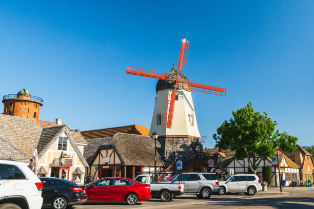 Main Street and Windmill in Solvang, a City in Southern California's Santa Ynez Valley. The City Has Known for its Traditional Danish Style Architecture. Solvang is a City in Santa Barbara County, California. In 1911 Group of Danes Established Here a Danish Community. Architecture Reflects Traditional Danish Style. Main Street, Street View, Windmill, Tourists. Solvang, California/USA -May 12, 2019 green valley denmark stock pictures, royalty-free photos & images