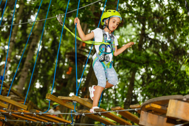 menina feliz da escola que aprecia a atividade em um parque de escalada da aventura em um dia de verão - education high up sport sports helmet - fotografias e filmes do acervo