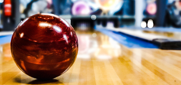 photo of a red bowling ball on the track taken in portrait.