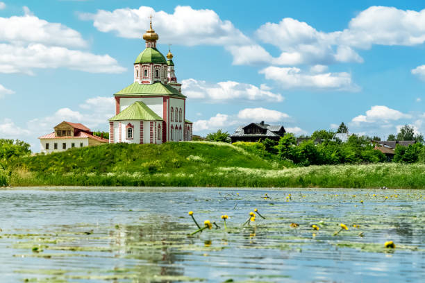 Beautiful old church by the lake under the blue summer sky with light clouds. Toned. stock photo