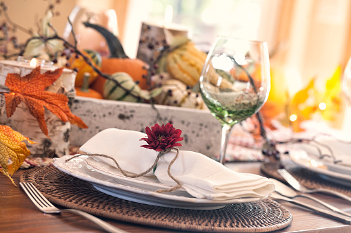 Autumn Thanksgiving holiday dining table place setting with a centerpiece of pumpkins and gourds