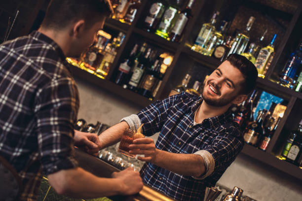 istock Young bartender standing at bar counter giving customer cocktail cheerful 1165800374