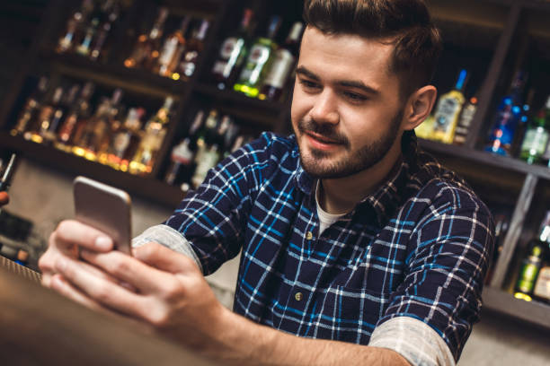 istock Young bartender leaning on bar counter browsing internet joyful close-up 1165800389