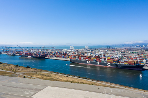 Aerial view of containers and container ships in the Oakland port. Ships docked in the Oakland Estuary on a sunny day. Contaners as far as the eye can see.