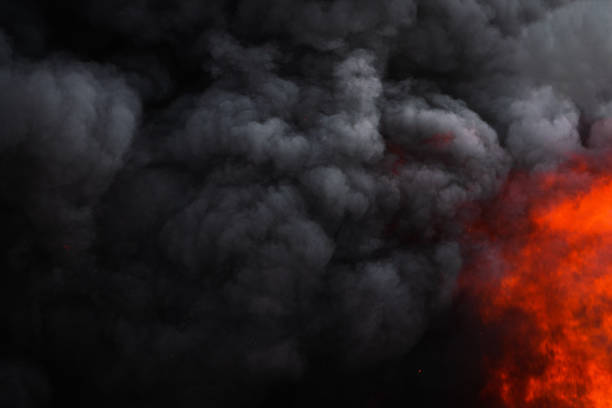 Flames strong red fire, dramatic clouds motion blur of black smoke covered sky stock photo