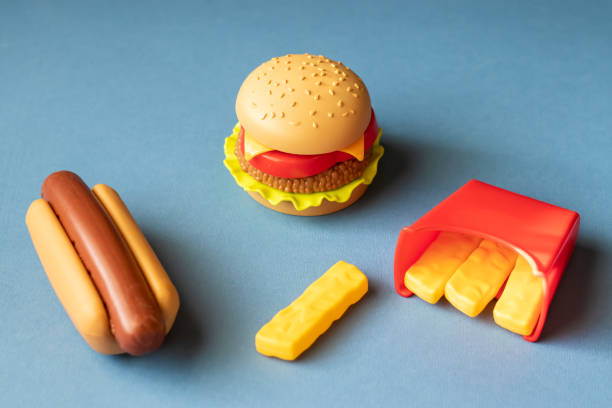 Plastic burger, salad, tomato, frying potatoes with a hot dog on a blue background. Horizontal orientation. Children's toy. The concept of harmful artificial food. Plastic Not organic. Not healthy. stock photo