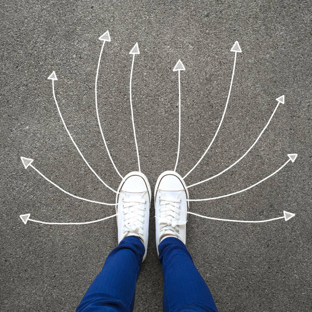 Feet and arrows on road. Solution. Selfie woman wearing white shoes or sneakers on concrete background with arrows. Success, creative, choice and idea concept. Top view. Feet and arrows on road. Solution. Selfie woman wearing white shoes or sneakers on concrete background with arrows. Success, creative, choice and idea concept. Top view. Foot and legs seen from above. running shoes on floor stock pictures, royalty-free photos & images