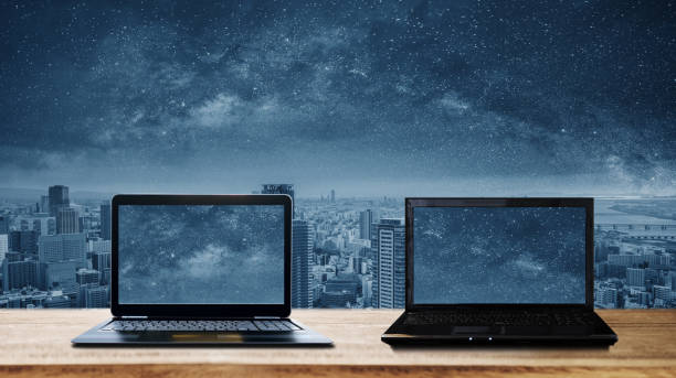istock Two computer laptops on wooden desk and futuristic city background 1165834449