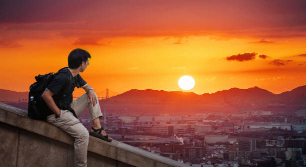 a man with backpack looking at Osaka city view in sunset with the sun a man with backpack looking at Osaka city view in sunset with the sun osaka city photos stock pictures, royalty-free photos & images