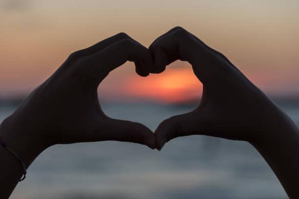 istock Heart with hands at dawn 1165837906