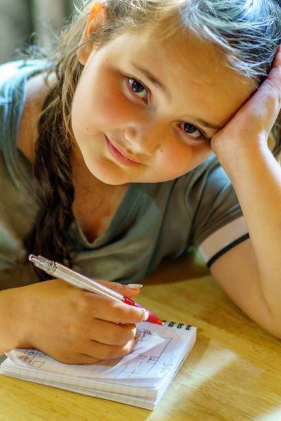 istock Eleven year old girl writing in notepad 1165841217