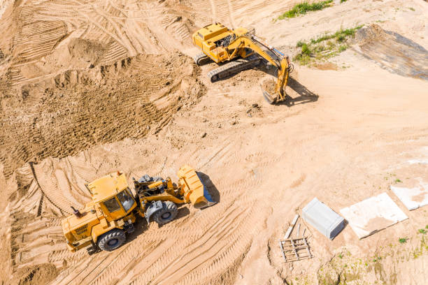 istock yellow earthmover and excavator doing ground works during road construction 1165841285