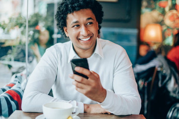 istock Afro-american man enjoying cup of coffee and using smart phone 1165842028