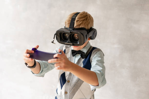istock Young boy in VR helmet posing on background of gray wall 1165843934