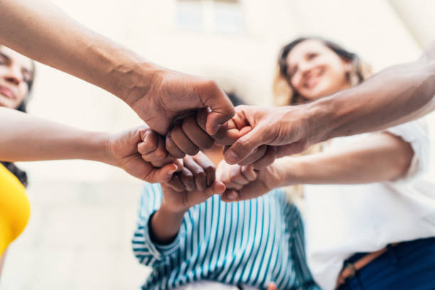 Unity Group of multi-ethnic young people stacking hands together sea of hands stock pictures, royalty-free photos & images
